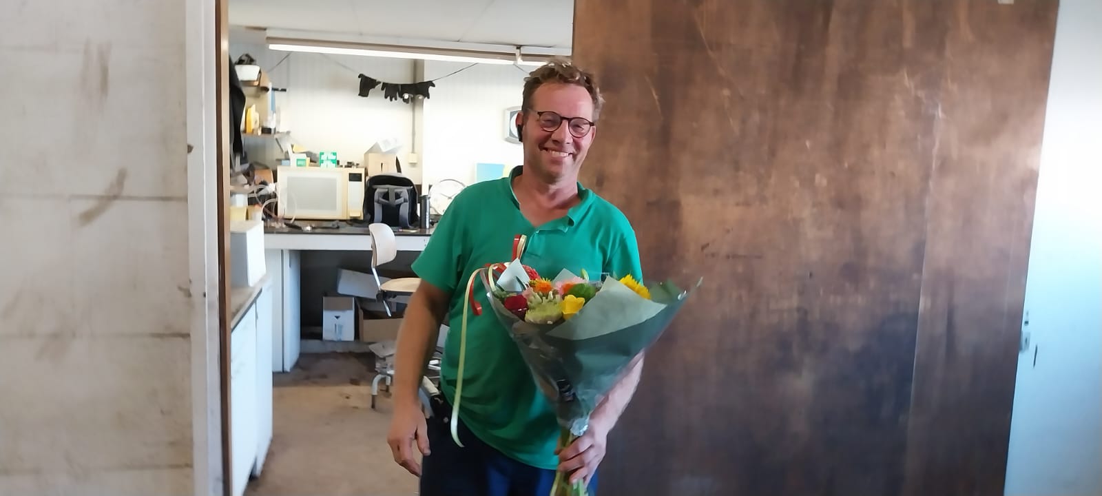 man ontvangt bloemen omdat hij genomineerd is voor de Hartstikke Sociaal Bokaal